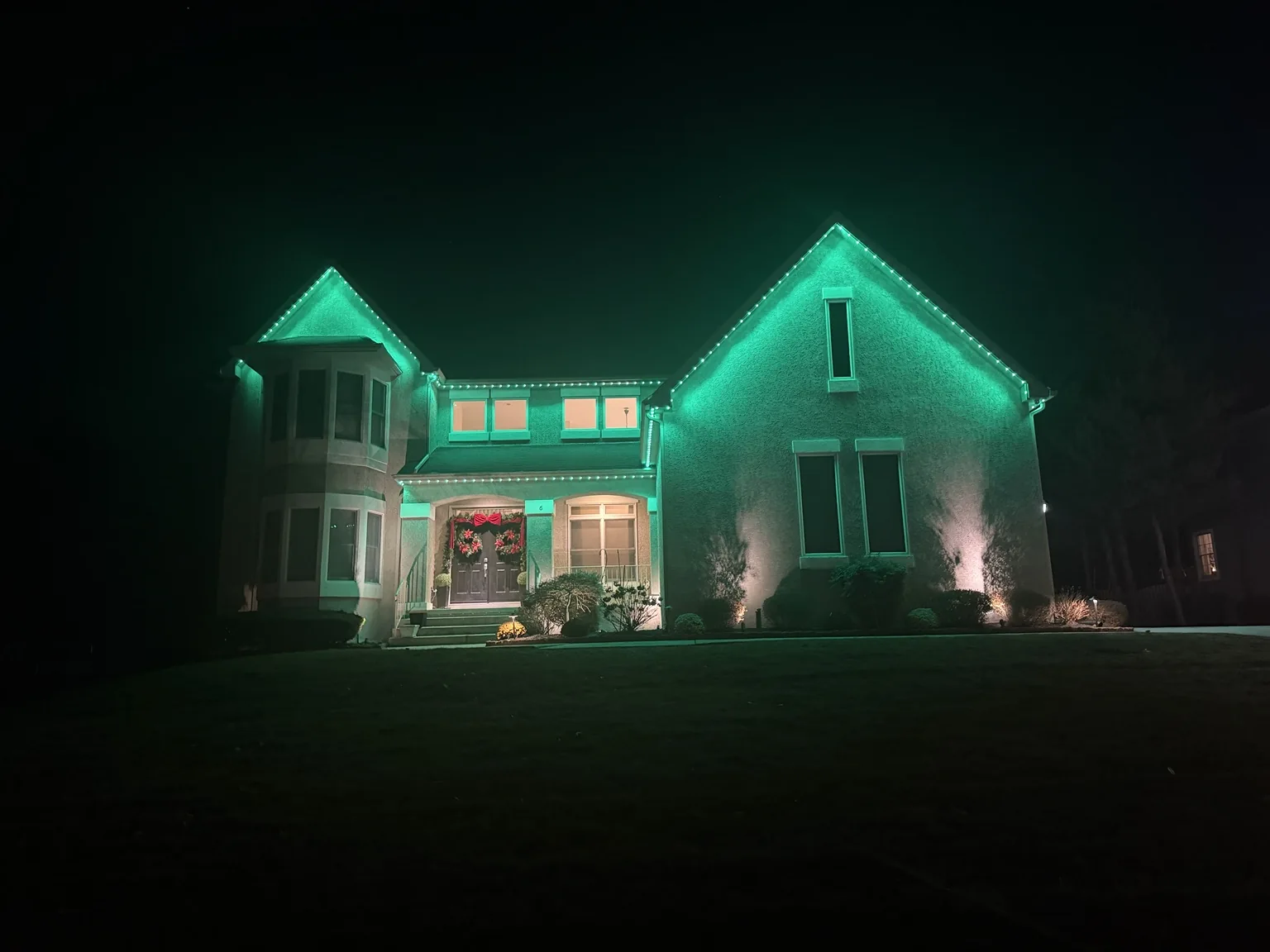 Green permanent lighting washing down the exterior of a home