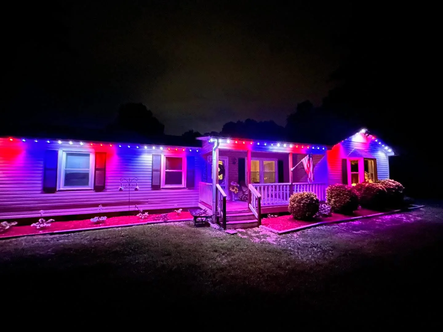 Red blue and white roofline lights washing a single story house